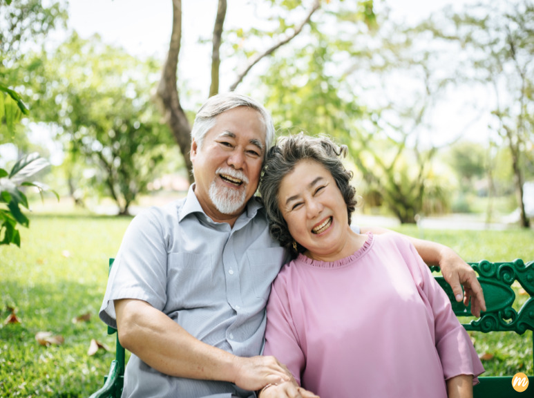 man and woman sitting on bench in front of beach